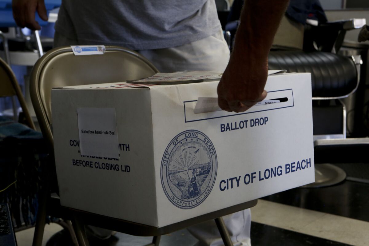 A voter deposits a ballot in the ballot box during election day at Utah's Barber Shop in Long Beach on June 3, 2014.