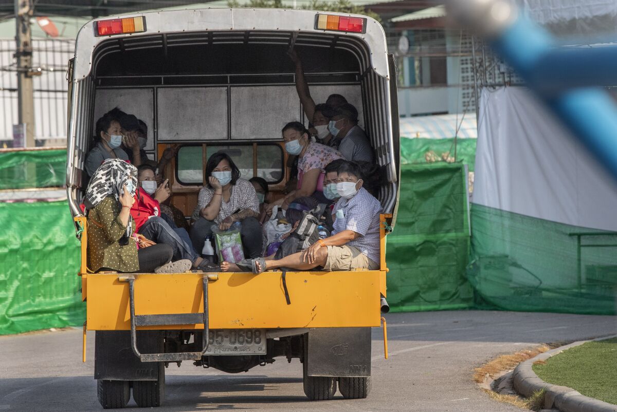 Migrant workers and their families ride in the back of a truck as they wait to be admitted to a field hospital for COVID-19 patents, Monday, Jan. 4, 2021, in Samut Sakhon, South of Bangkok, Thailand. Thailand reported on Tuesday, Jan. 5, 2021, over 500 new coronavirus cases, most of them migrant workers who already were isolated, and the government said it was tightening movements of people around the country. (AP Photo/Gemunu Amarasinghe)