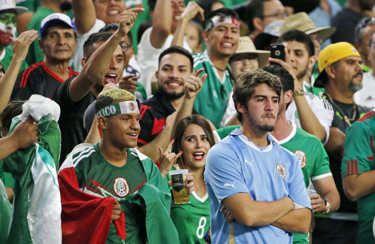 A dejected Uruguay fan, right, is surrounded by c 