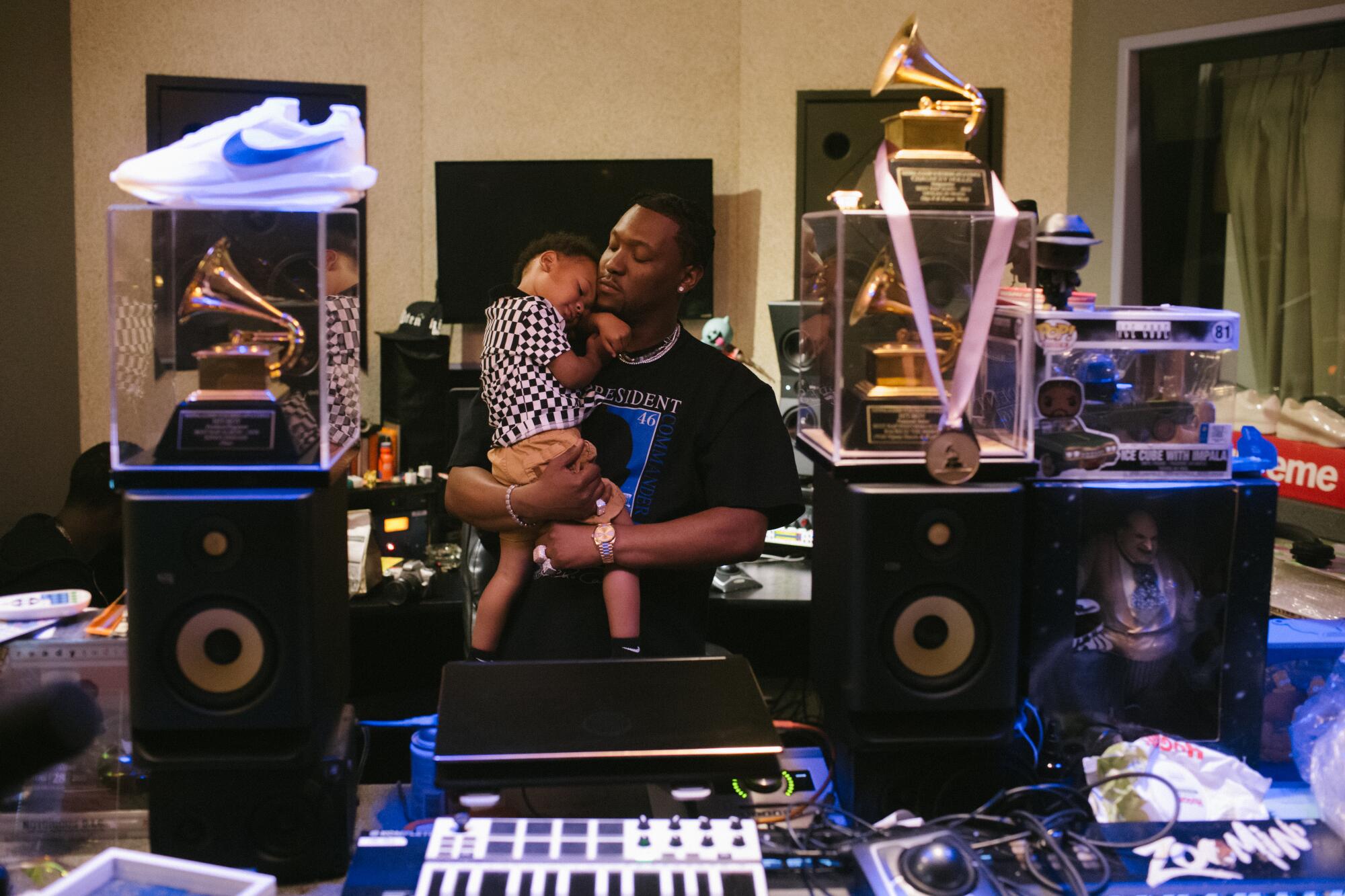 A music producer in the studio, holding a small child