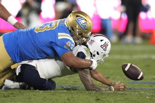 Arizona quarterback Jayden de Laura fumbles the ball while being tackled by UCLA defensive lineman Jay Toia 