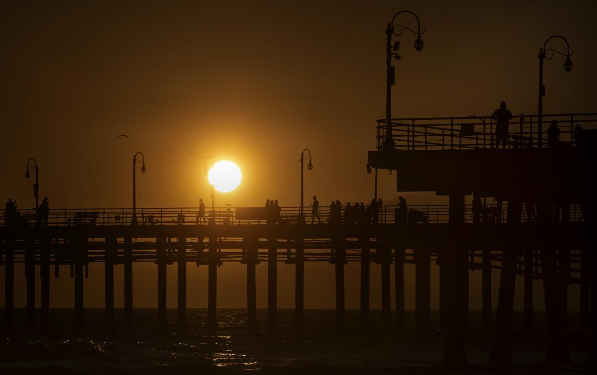 People take in the view as the sun sets beyond the Santa Monica Pier. 