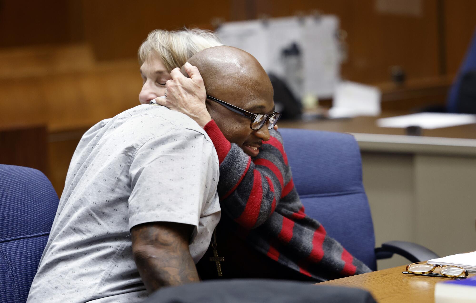 A man and a woman hug in a courtroom.
