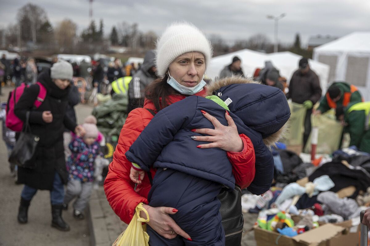 A woman carries her child as she arrives at the Medyka border crossing after fleeing from the Ukraine