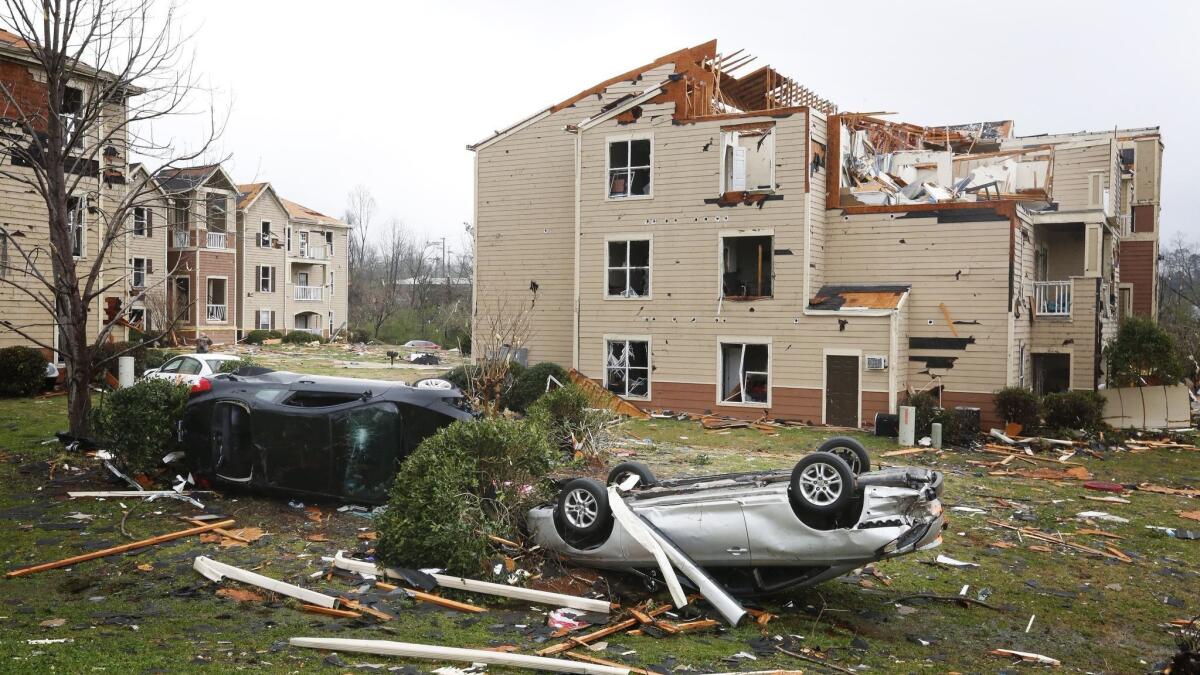 Two overturned cars lie in front of a storm-damaged apartment complex in Jacksonville, Ala., on March 20.