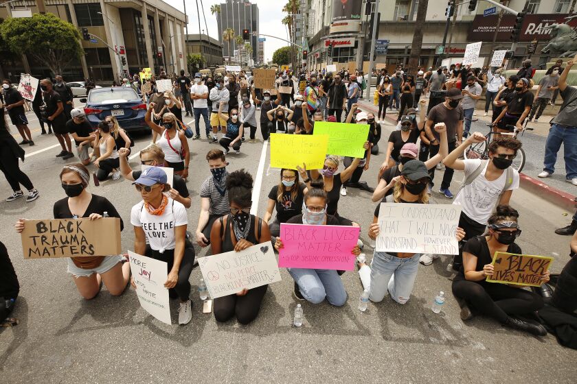 LOS ANGELES, CA - JUNE 02: Protestors take a knee in front of LAPD officers as they close Sunset Blvd at Vine Street in Hollywood while protesters made of mostly students marched through Hollywood Tuesday afternoon to protest the death of George Floyd during an arrest in Minneapolis last week. The group gathered at the intersection of Hollywood Blvd and Vine Street for a peaceful demonstration and marched through parts of Hollywood encountering LAPD officers and National Guardsmen. Hollywood on Tuesday, June 2, 2020 in Los Angeles, CA. (Al Seib / Los Angeles Times)