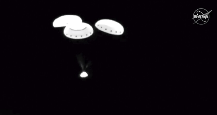 In this image taken from NASA video, the Starliner capsule descends into the Army's White Sands Missile Range on Sunday in White Sands, N.M.