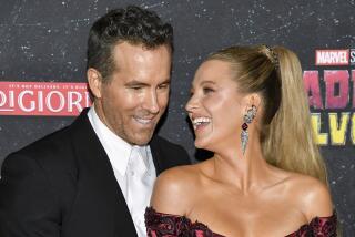 Ryan Reynolds standing close to Blake Lively as both smile and laugh while wearing semiformal attire
