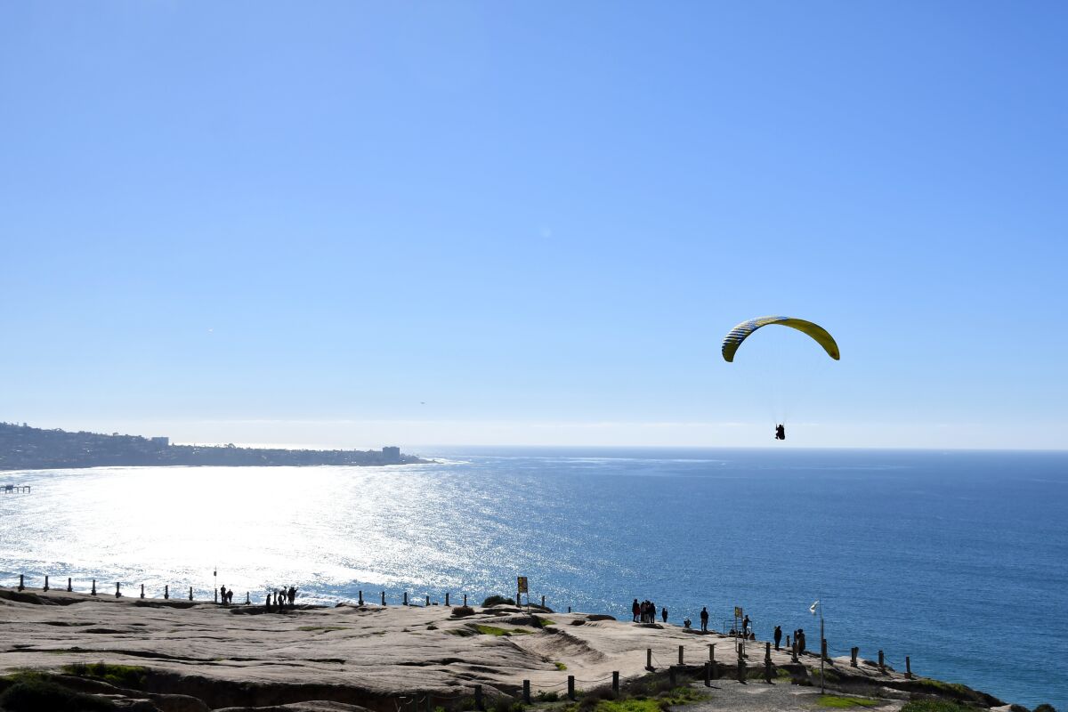 A glider hovers above Torrey Pines Gliderport, with the ocean beyond.
