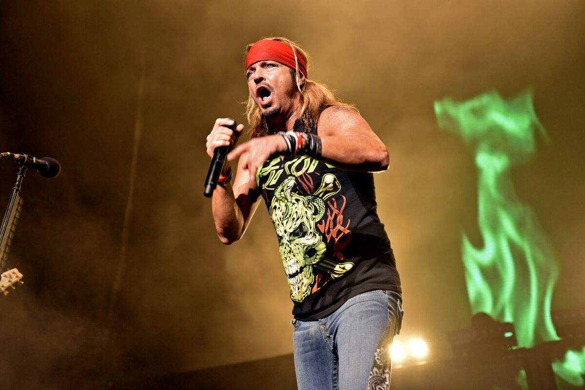 Bret Michaels holds a microphone while performing on stage