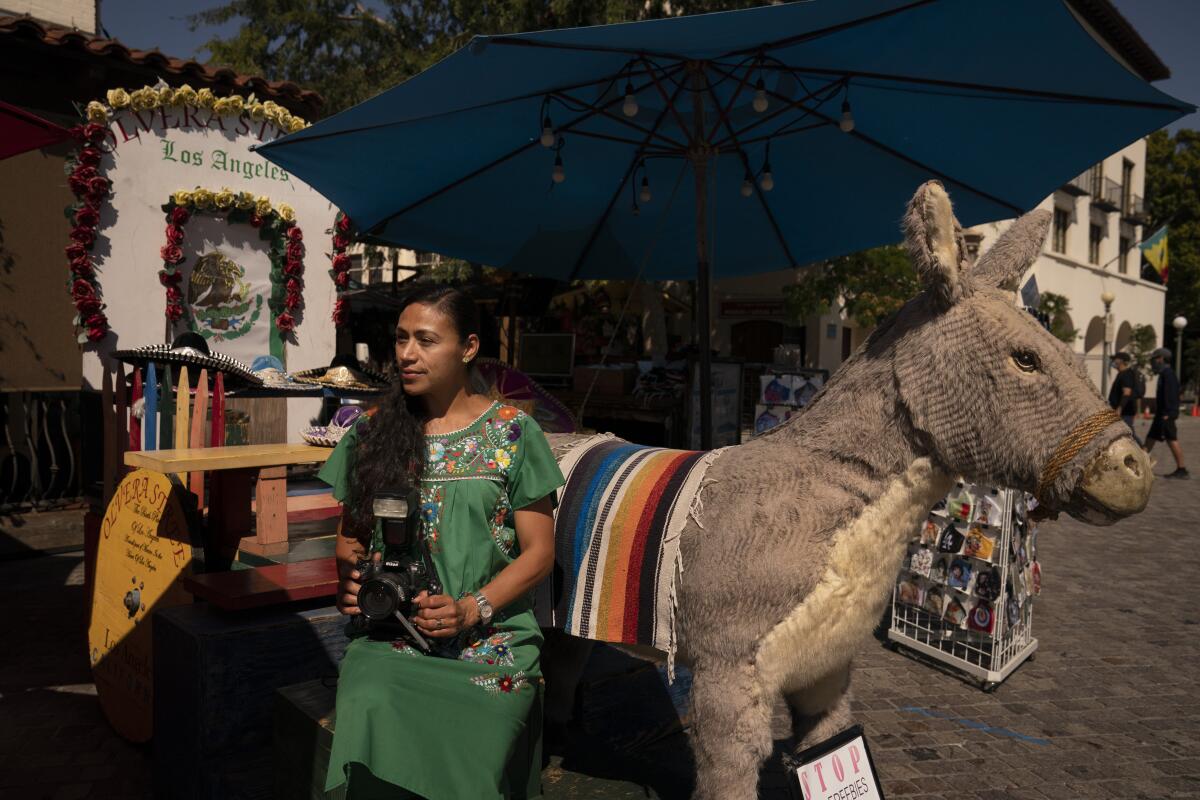 Photographer Carolina Hernandez sits for a photo next to a stuffed donkey.