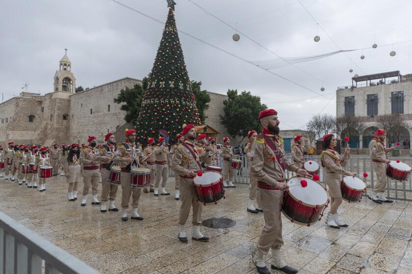 Palestinian scout bands parade through Manger Square at the Church of the Nativity, traditionally recognized by Christians to be the birthplace of Jesus Christ, ahead of the midnight Mass, in the West Bank city of Bethlehem, Thursday, Dec. 24, 2020. Few people were there to greet them as the coronavirus pandemic and a strict lockdown dampened Christmas Eve celebrations. (AP Photo/Nasser Nasser)