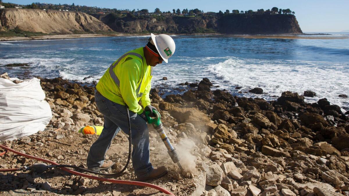 Work crews use jackhammers to demolish the "fort" built by surfers on the shoreline of Lunada Bay.