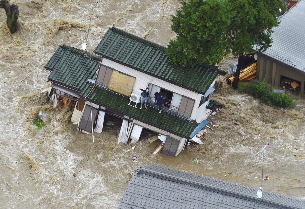 A person inside a house damaged by flooding waves to a helicopter in Joso, Japan, on Sept. 10.