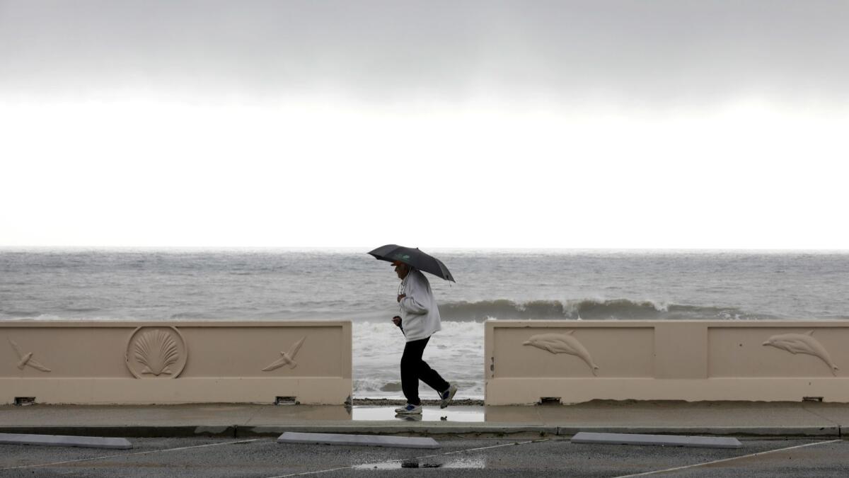 A walker braves the rain along Zuma Beach in Malibu in an undated photo.