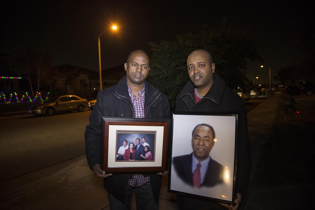 Berhane Gebreslassie, left, brother of shooting victim Isaac Amanios, and Zeke Gebrekidane, nephew, with family photos outside the family's home in Fontana.
