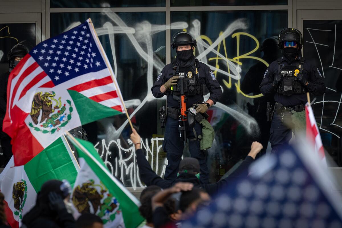 Federal officers and the National Guard protect the federal building as demonstrators protest immigration raids on Tuesday.