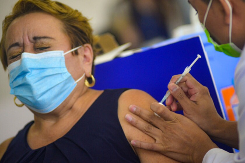SAN SALVADOR, EL SALVADOR - OCTOBER 12: A woman reacts as she receives a jab of the Moderna vaccine as part of the COVID-19 vaccination campaign on October 12, 2021 in San Salvador, El Salvador. All Salvadorans over 18 years old who have been fully vaccinated can now receive a booster third dose with the Moderna vaccine. (Photo by Roque Alvarenga/APHOTOGRAFIA/Getty Images)