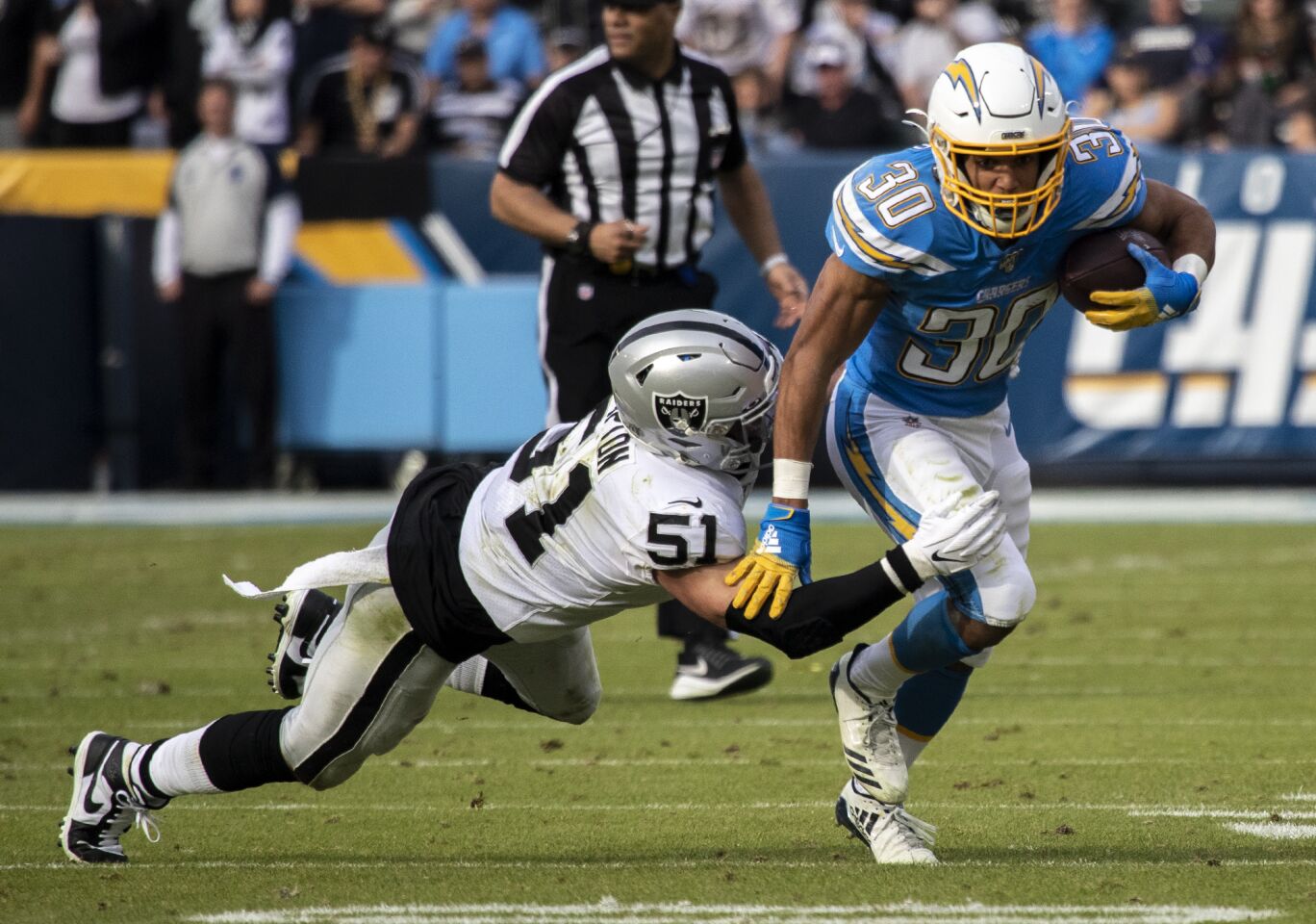 Chargers running back Austin Ekeler evades a tackle by Oakland Raiders inside linebacker Will Compton.