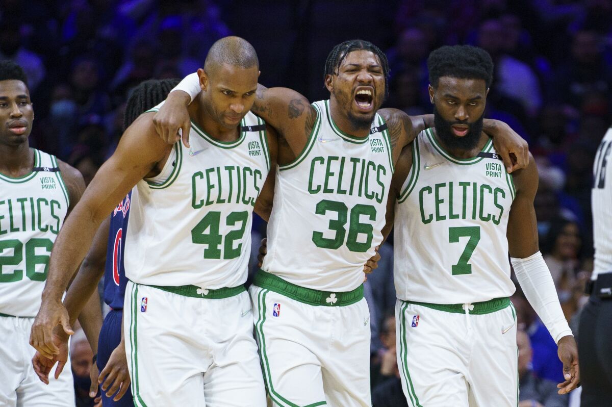 Boston Celtics' Marcus Smart, center, gets helped off the court by Al Horford, left, and Jaylen Brown, right, during the first half of the team's NBA basketball game against the Philadelphia 76ers, Tuesday, Feb. 15, 2022, in Philadelphia. (AP Photo/Chris Szagola)
