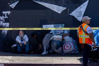 Hollywood, CA - August 15: A homeless man waits for transportation to housing as Mayor Karen Bass' Inside Safe program employees along with the Los Angeles Sanitation Bureau clean up homeless encampments along Hollywood Blvd. and Gower Street on Thursday, Aug. 15, 2024 in Hollywood, CA. (Brian van der Brug / Los Angeles Times)