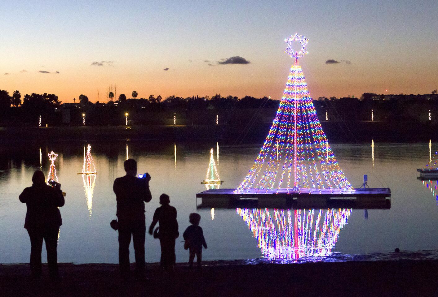 A family gathers to observe the tallest of the Christmas decorations at the Newport Dunes Waterfront Resort's holiday season kick-off event at dusk on Friday. The event included performances by the O.C. Children's Song Group, the Corona del Mar High School choir, and a visit by Santa Claus.