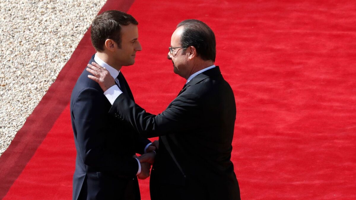 New French President Emmanuel Macron, left, shakes hands Sunday with outgoing President Francois Hollande at the Elysee Palace.