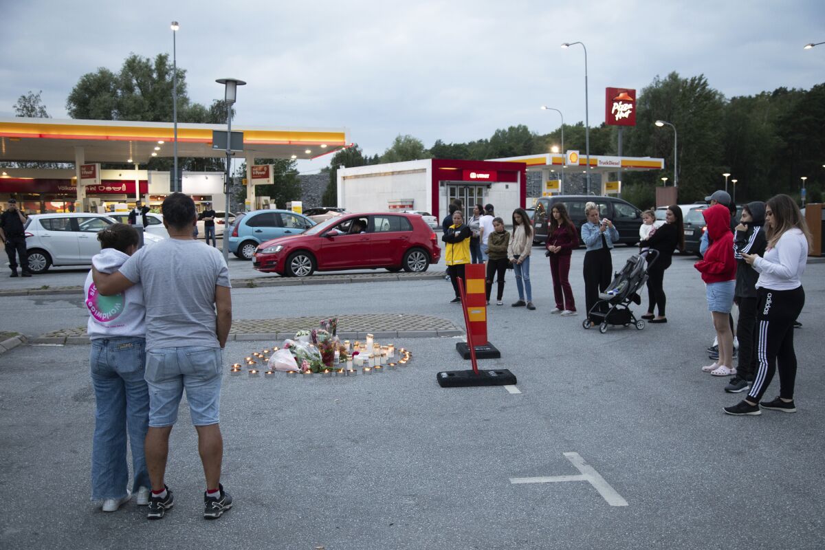 Flowers and candles are placed Sunday Aug. 2, 2020 near where a twelve-year-old girl was shot and killed near a petrol station in Botkyrka, south of Stockholm, Sweden. (Ali Lorestani//TT via AP)