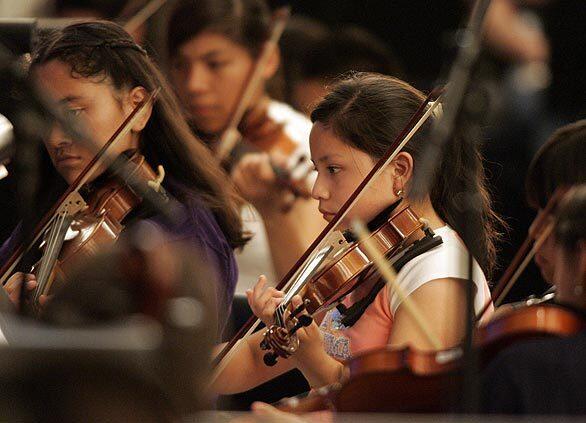 Arlette Romero, 11, center, plays her violin during a rehearsal for the YOLA Expo Center Youth Orchestra's debut at the Hollywood Bowl as part of the "¡Bienvenido Gustavo!" concert.