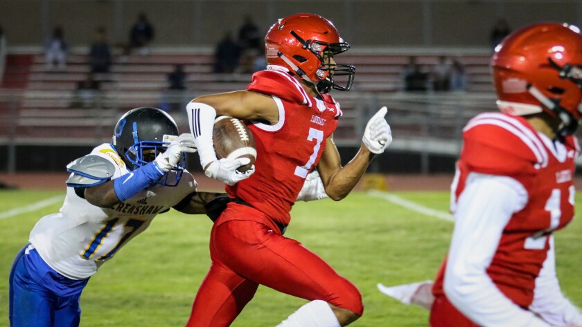 Lawndale's Makell Esteen tries to outrun the tackle attempt by a Crenshaw defensive back after making a catch during a game Sept. 14, 2018.