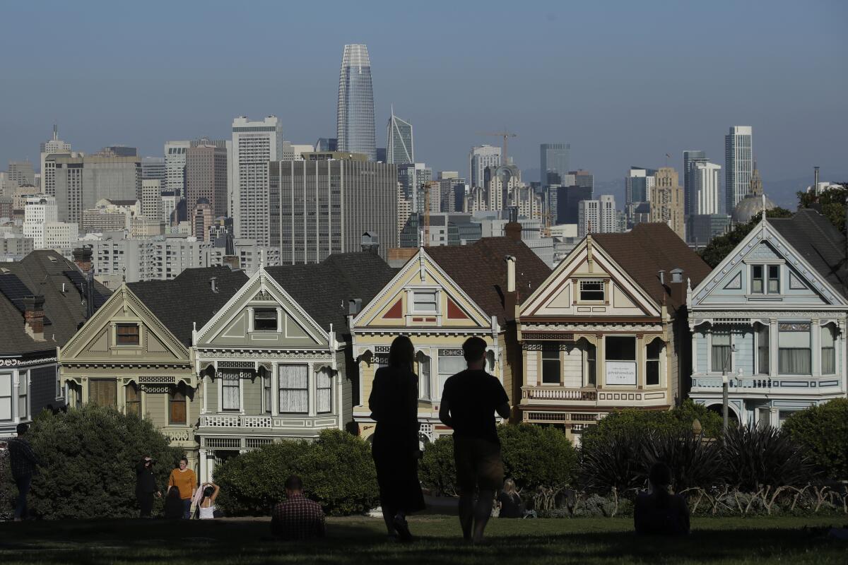 Visitors look toward a row of historical homes in San Francisco.