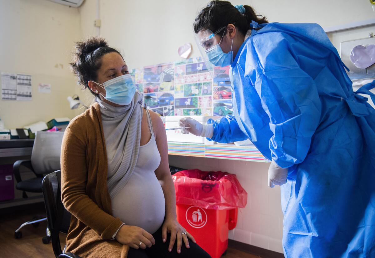 A nurse gives a shot of the Pfizer vaccine for COVID-19 to a pregnant woman.