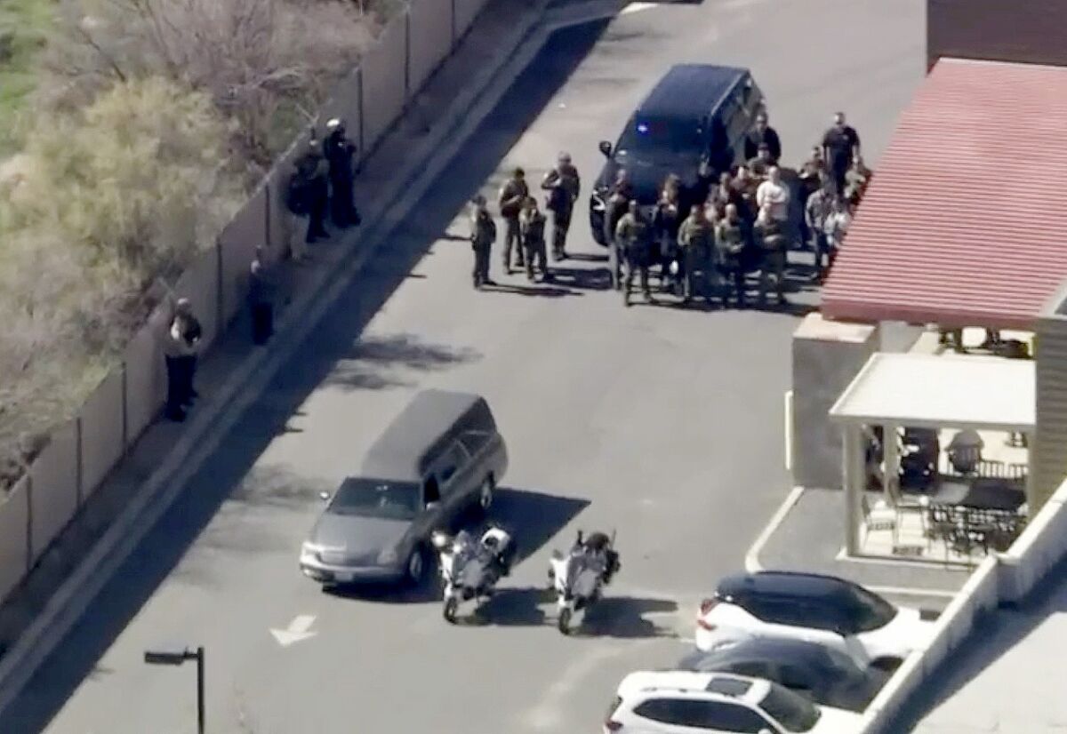 Aerial view of a hearse with police motorcycles next to it, followed by a group of deputies in uniform next to an SUV
