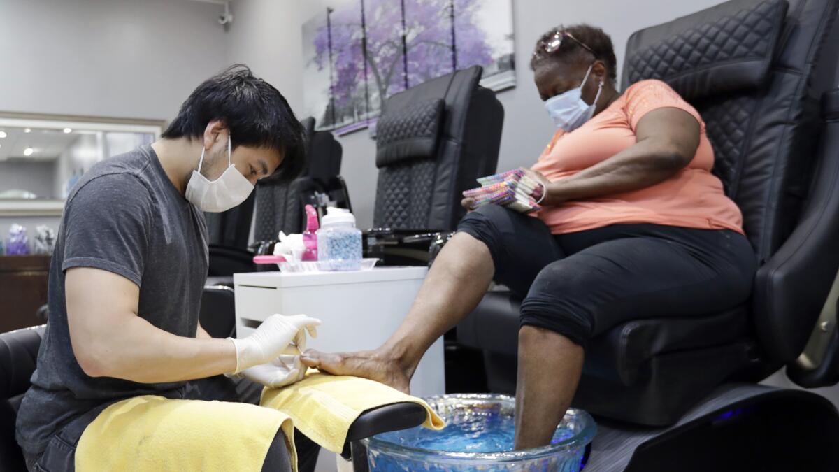 In Lyndhurst, Ohio, Nick Bun, left, gives a pedicure to Delena Dunn on Friday. Republican Ohio Gov. Mike DeWine has said that 90% of the state's economy will be reopened this weekend.