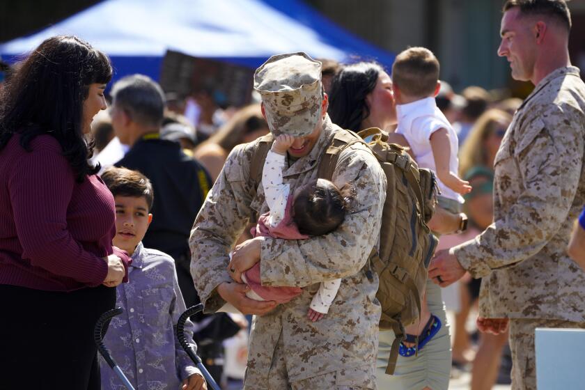 Oceanside, CA - October 03: At the homecoming at Camp Pendleton on Sunday, Oct. 3, 2021 in Oceanside, CA., Lance Cpl. Nathan Sweet holds his 8-month old daughter, Sabrina, as his wife Selena and son, Damian also welcome Nathan home. Marines from 2nd Battalion 1st Marines lost 9 Marines and sailor in Afghanistan during the massive evacuation operation in August of this year. (Nelvin C. Cepeda / The San Diego Union-Tribune)