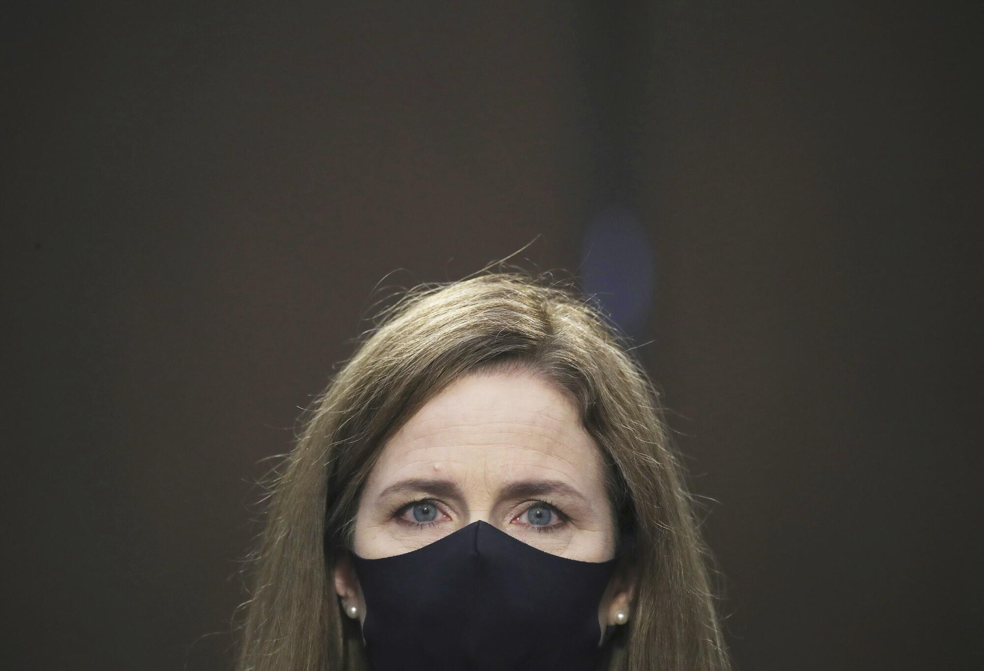 A closeup of Amy Coney Barrett in a black protective mask.