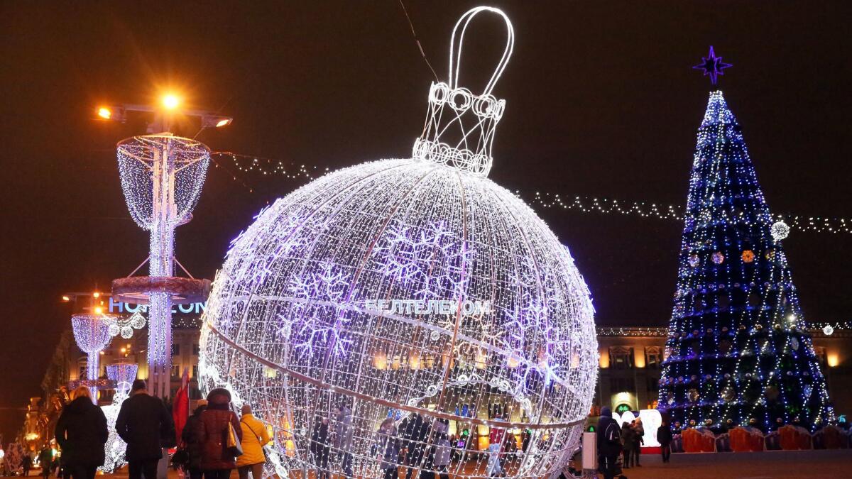 People walk past giant illuminated holiday ornaments at Octyabrskaya Square in Minsk, Belarus on Dec. 18.