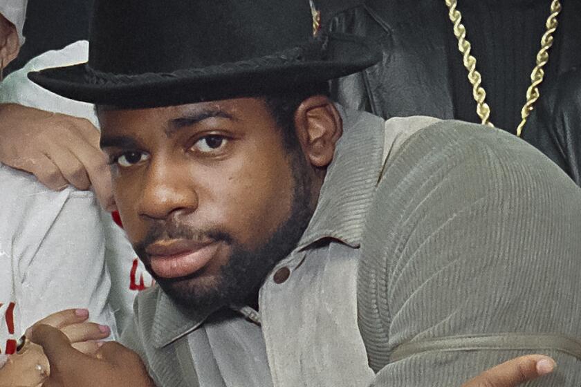 Run-DMC's Jam Master Jay wearing a hat as he crosses his arms in an X and points his index fingers