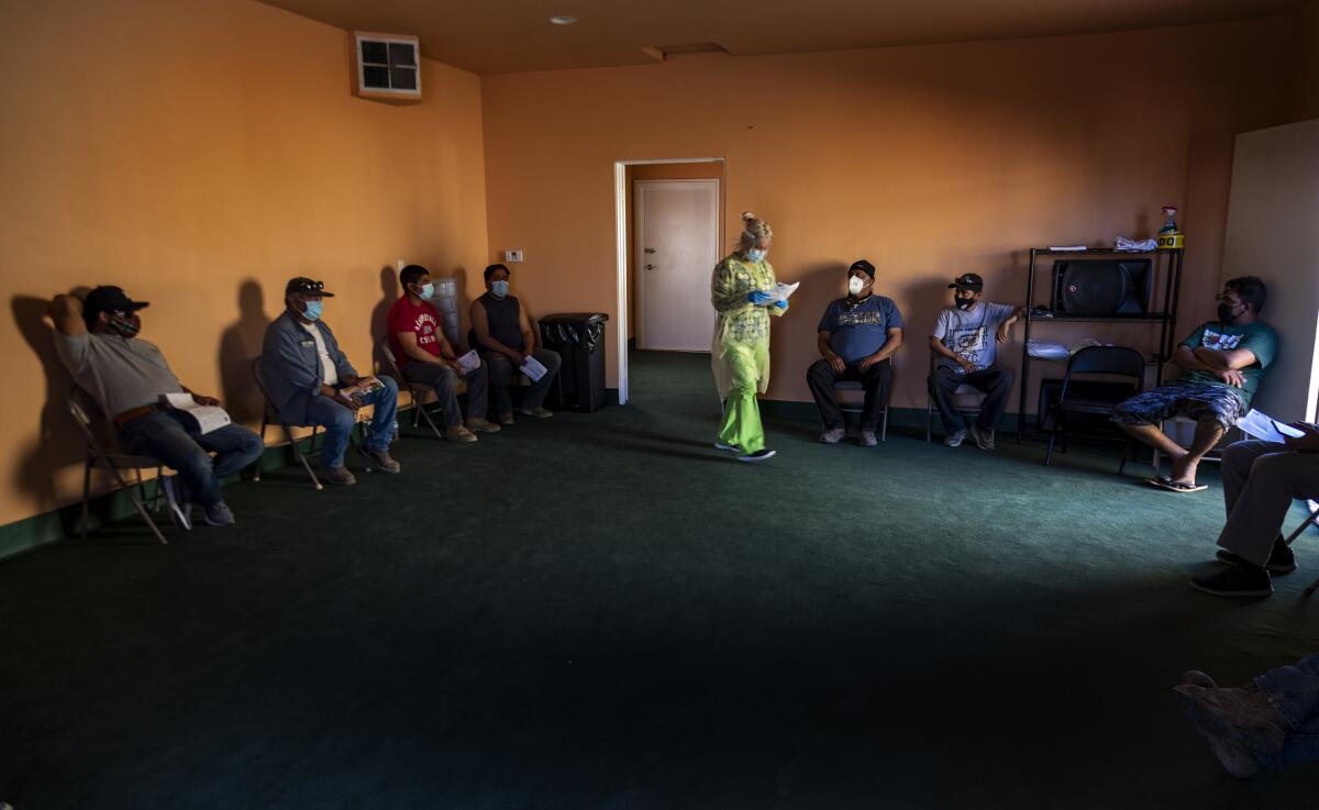 Farmworkers wait in folding chairs to get the COVID-19 vaccine 