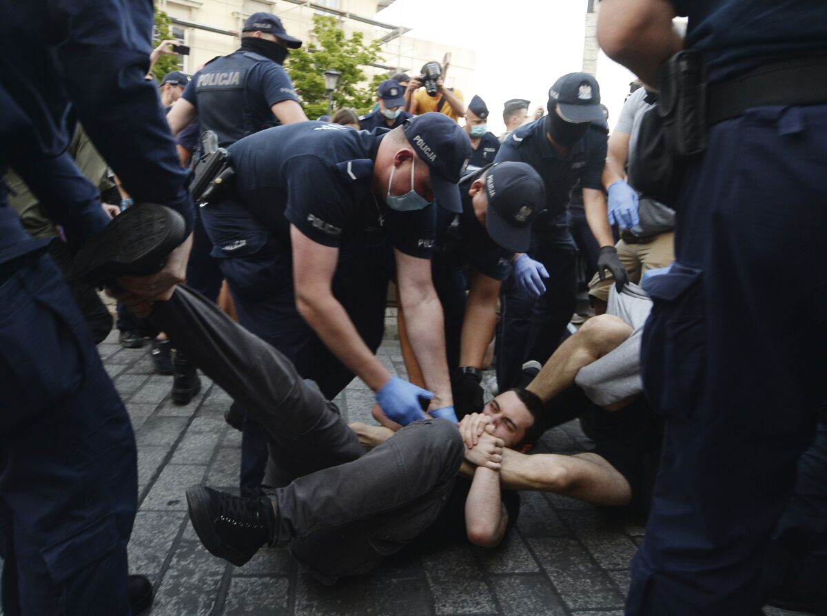 Police scuffle with pro-LGBT protesters angry at the arrest of an LGBT activist in Warsaw, Poland on Friday, Aug. 7, 2020. The incident comes amid rising tensions in Poland between LGBT activists and a conservative government that is opposed to LGBT rights. (AP Photo/Czarek Sokolowski)