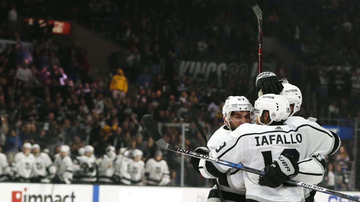 The Kings' Alec Martinez (27), Jake Muzzin (6) and Alex Iafallo (19) celebrate Martinez's third-period goal against Carolina on Dec. 2 at Staples Center.