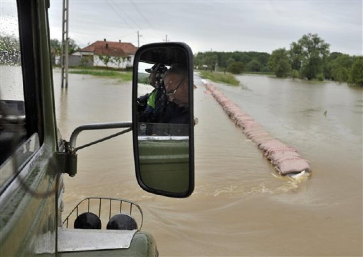 Hungarian farmers drive their trucks through an over-flooded road near the village of Kiskinizs, northeastern Hungary, Tuesday, May 18, 2010. Several swollen rivers causing floods throughout Hungary, while roads remain closed due to the unusual wet weather and heavy rains. Heavy rains that began in central Europe last weekend also are causing flooding in areas of Poland , Slovakia and the Czech Republic, with rivers bursting their banks and inundating low-lying homes and roads, and cutting off villages. (AP Photo/Bela Szandelszky)