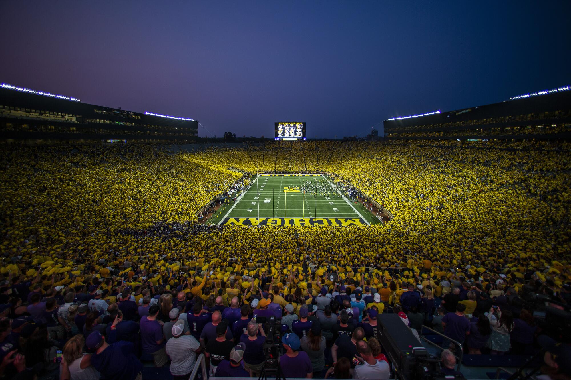 The Michigan Marching Band takes the field to a "maize out" crowd at Michigan Stadium