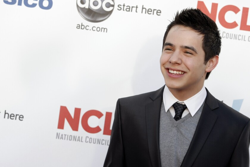 A man posing in a black suit.