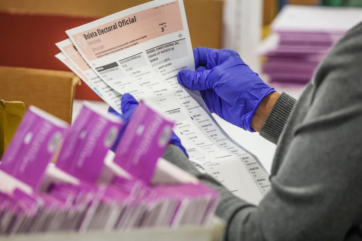 L.A. County worker holds ballot with gloved hands 
