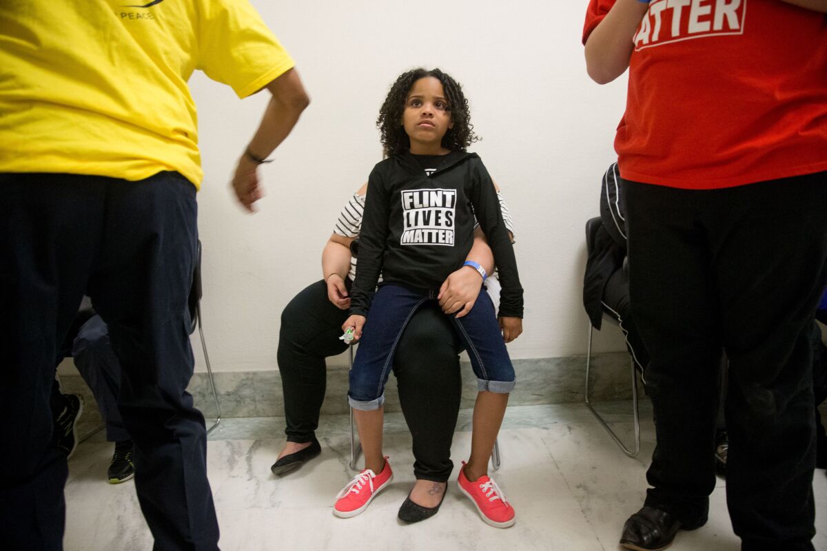 Mari Copeny, 8, of Flint, Mich. sits on the lap of her mother, Lulu Brezzell as they wait outside the room where Michigan Gov. Rick Snyder and EPA Administrator Gina McCarthy testify before a House Oversight and Government Reform Committee hearing in Washington.