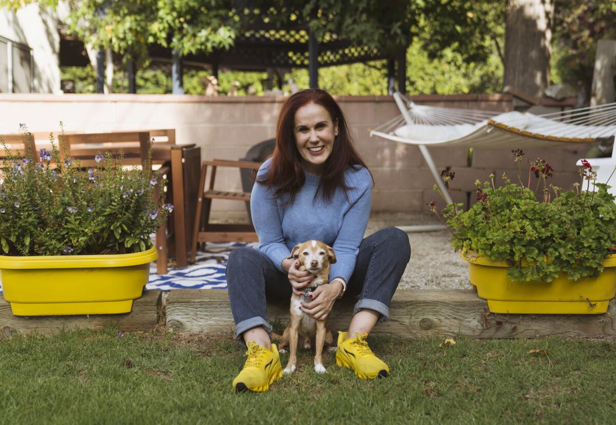 Ildiko Tabori sits on a step with her dog Johnny Carson between her feet