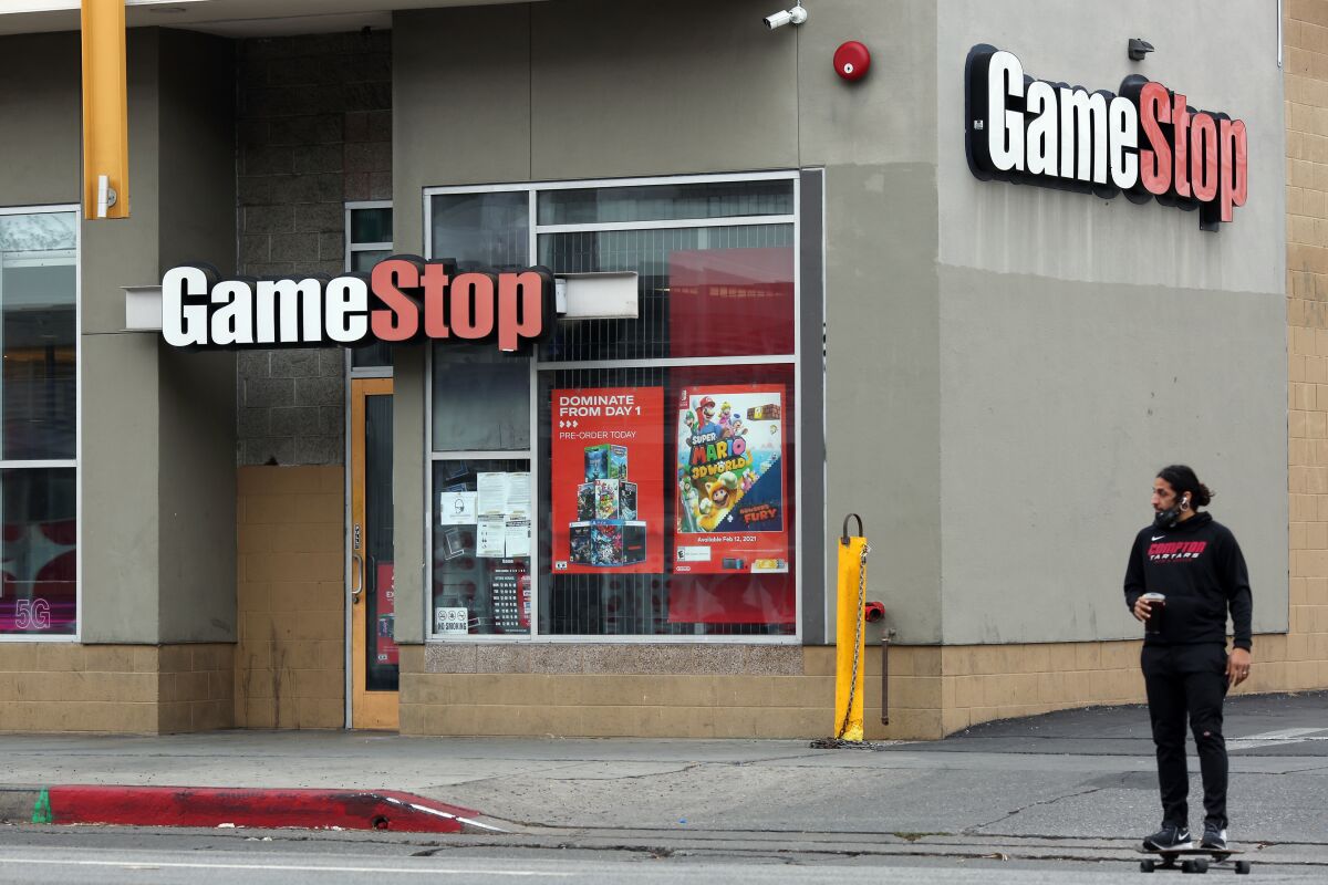 A man on a skateboard near a GameStop store