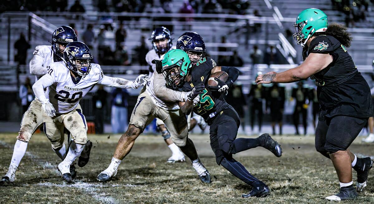 Jamari Ladd of Narbonne High tries to power his way through a tackle attempt by a Birmingham defender.