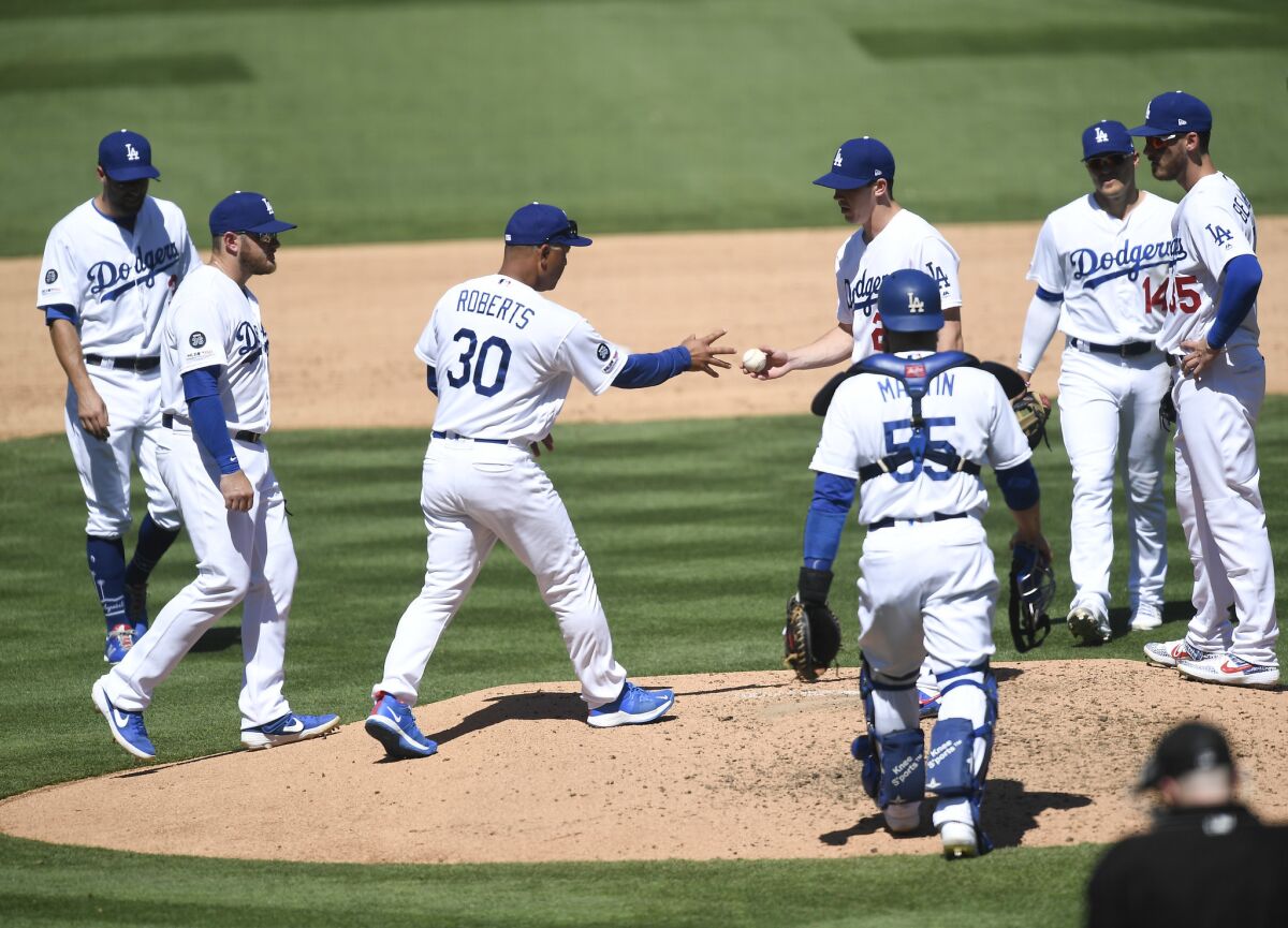 Dodgers manager Dave Roberts (30), takes starting pitcher Walker Buehler out of the game during the fourth inning of Sunday's 8-7 win over the Arizona Diamondbacks.